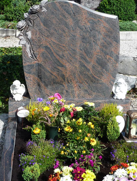 Schlichter Grabstein. An der linken Seite sind in den Stein eingearbeitete Rosen zu sehen